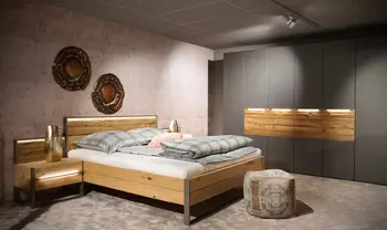 Modernes Schlafzimmer mit Massivholzbett, beleuchteten Nachttischen, großem Kleiderschrank in Grau-Holz-Optik und warm abgestimmter Wandgestaltung.
